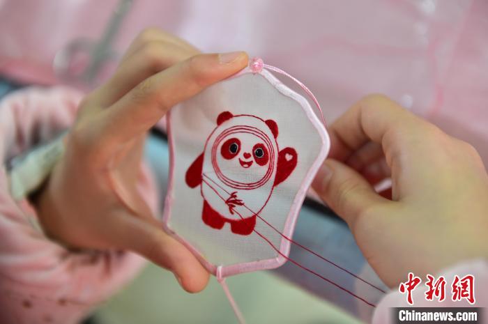 圖為一名小學生正在繡制2022年北京冬奧會吉祥物“冰墩墩”形象?！∮髟屏?攝