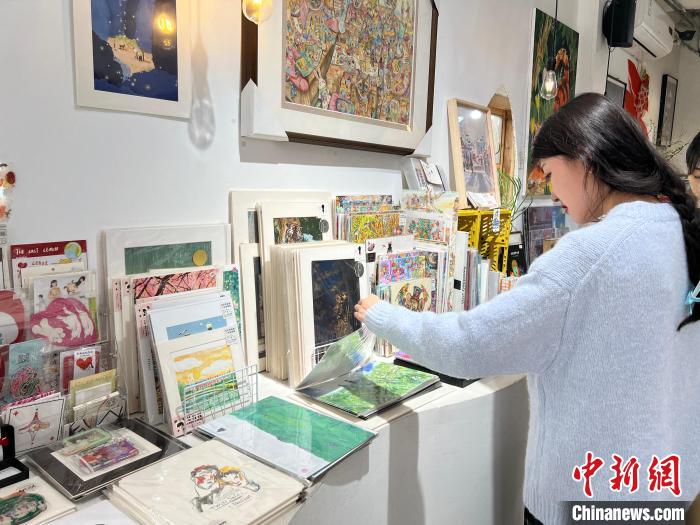 圖為藝術(shù)品商店內(nèi)，顧客挑選插畫作品?！＄婌?攝