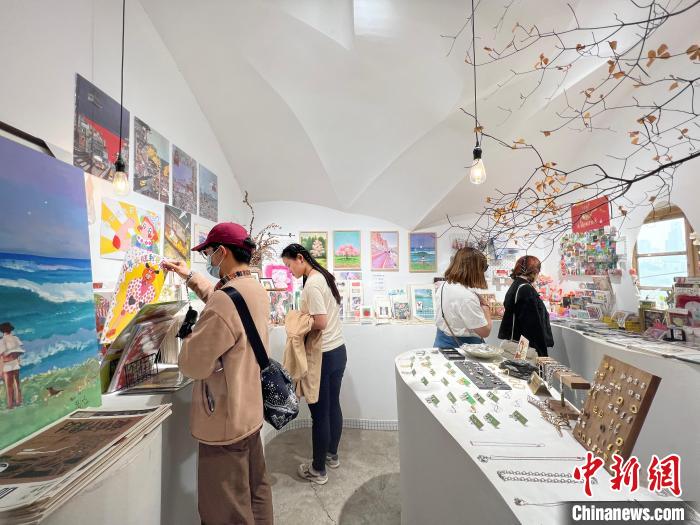 圖為藝術(shù)品商店內(nèi)，顧客挑選插畫作品?！＄婌?攝