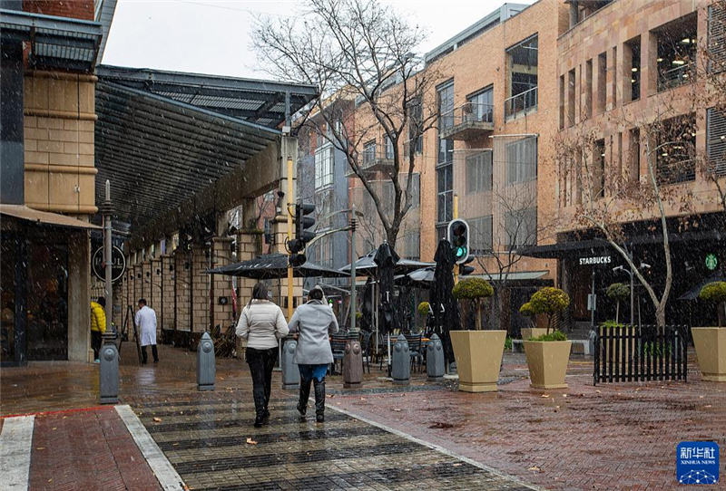 7月10日，在南非約翰內(nèi)斯堡一處商業(yè)區(qū)，人們在雪中行走。新華社記者 張譽(yù)東 攝