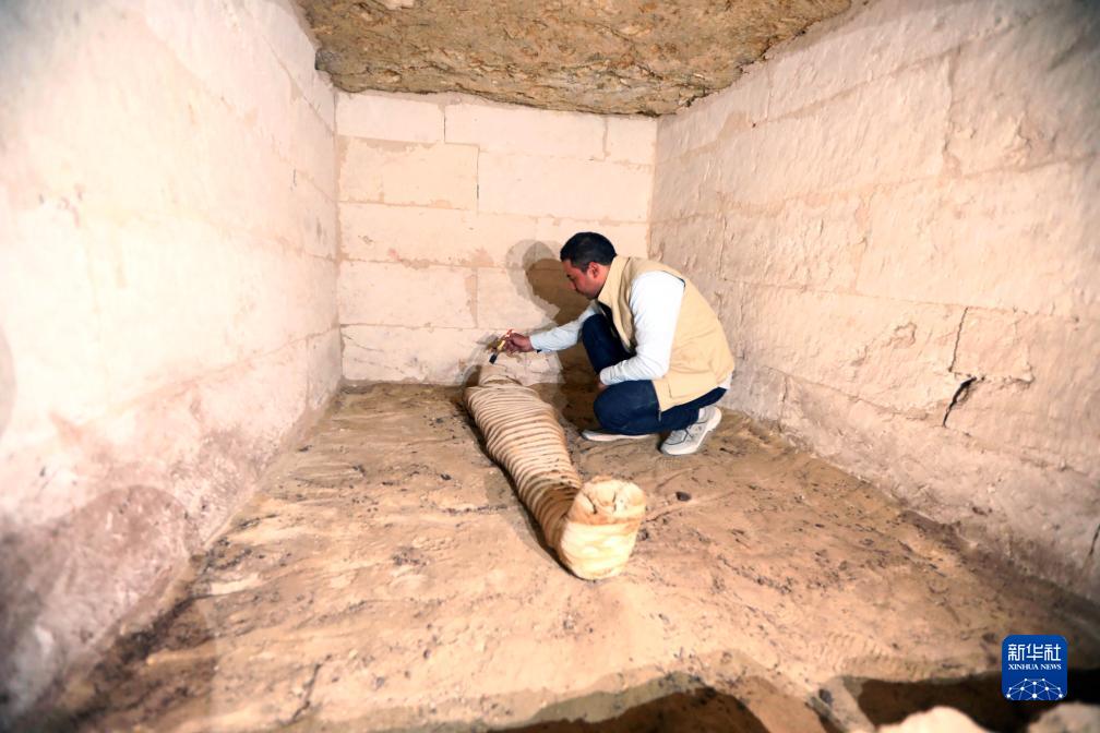 10月15日，在埃及明亞省考古現(xiàn)場，考古人員清理一座石鑿墓中的木乃伊。新華社發(fā)（艾哈邁德·戈馬攝）