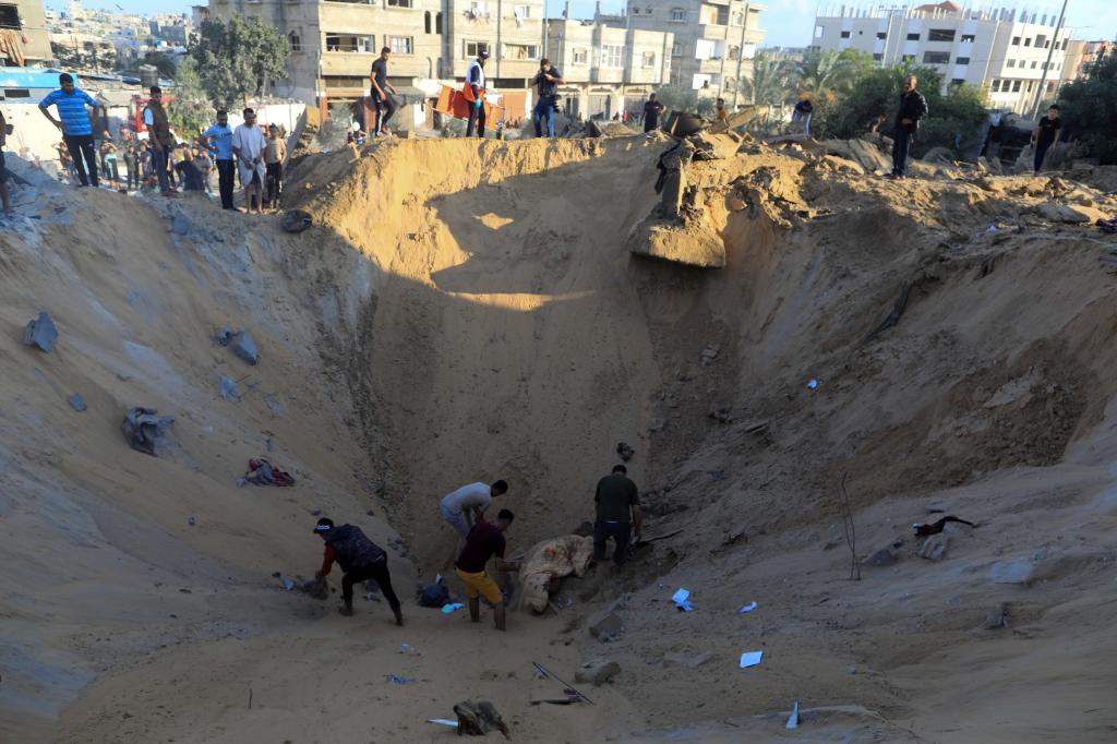 10月16日，在加沙地帶南部城市汗尤尼斯，人們在遭以色列襲擊后的建筑廢墟中救援傷者。 新華社發(fā)（亞西爾·庫迪 攝）