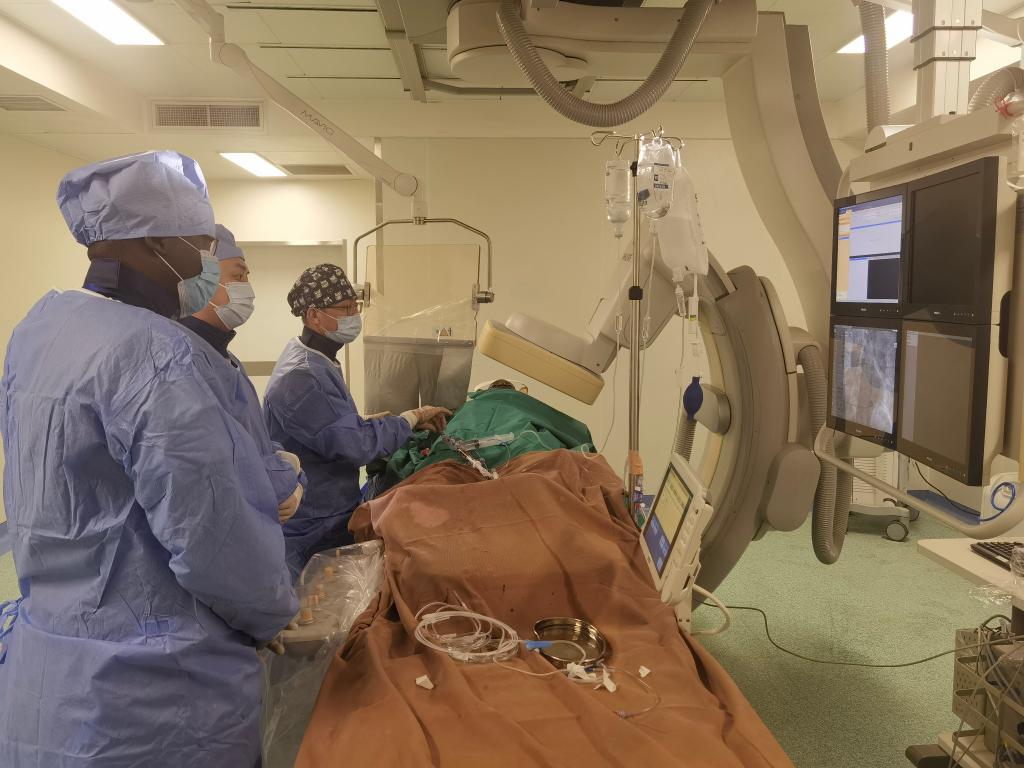 中國第29批援幾內(nèi)亞醫(yī)療隊(duì)隊(duì)員、首都醫(yī)科大學(xué)附屬北京天壇醫(yī)院心內(nèi)科副主任醫(yī)師王汝朋（右一）正在給患者做手術(shù)。（北京天壇醫(yī)院供圖）
