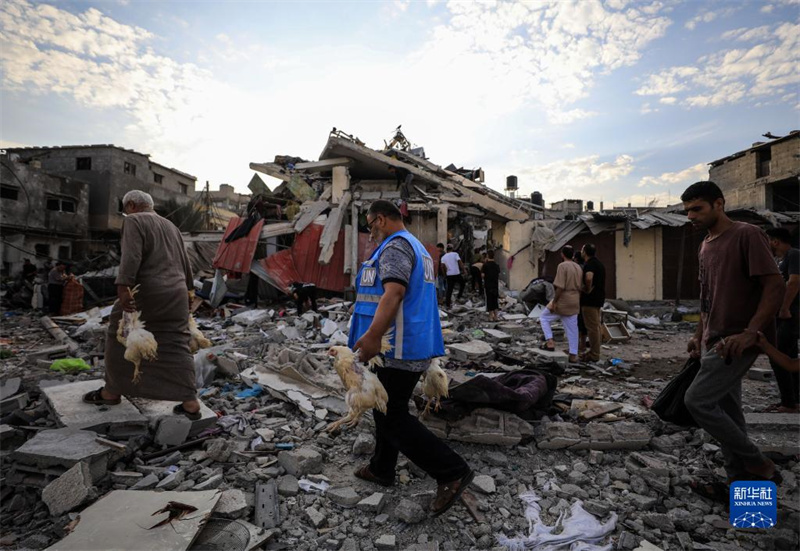10月27日，在加沙地帶南部城市汗尤尼斯，人們經(jīng)過以軍襲擊后的房屋廢墟。