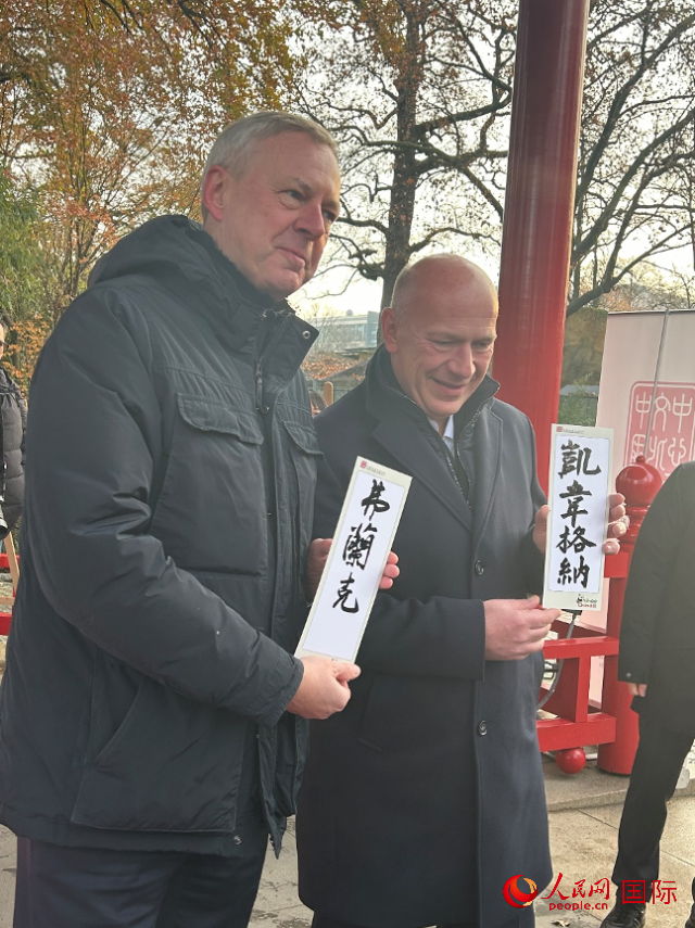 柏林市長韋格納（右）、動物園監(jiān)事會主席布魯克曼（左）手持中國文化中心工作人員現場手書的中文名字。人民網記者 徐馨攝