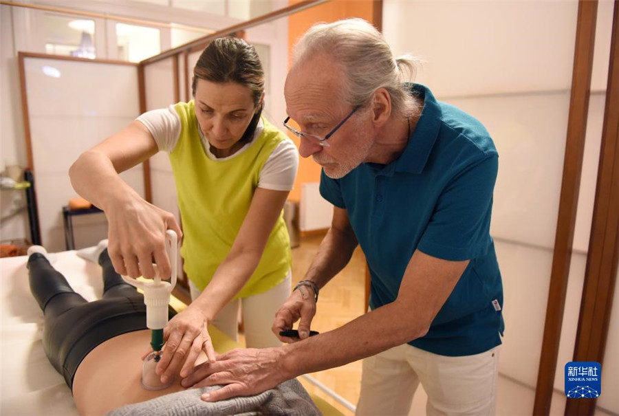 12月12日，在奧地利維也納，科格勒醫(yī)生（右）和助手在為病人進行拔罐治療。新華社記者 賀燦鈴 攝