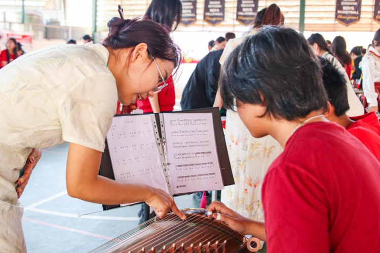 志愿者教師指導學生彈奏古箏。活動主辦方供圖