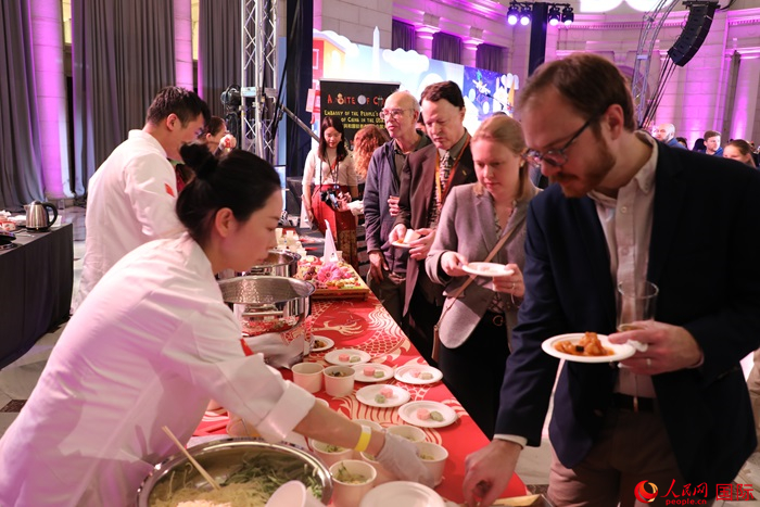 當(dāng)?shù)貢r(shí)間3月7日晚，華盛頓聯(lián)合車站廣場(chǎng)舉行駐美使團(tuán)“使館主廚挑戰(zhàn)賽”。圖為當(dāng)?shù)孛癖娫谥袊?guó)展臺(tái)前體驗(yàn)中國(guó)美食。人民網(wǎng)記者 李志偉攝