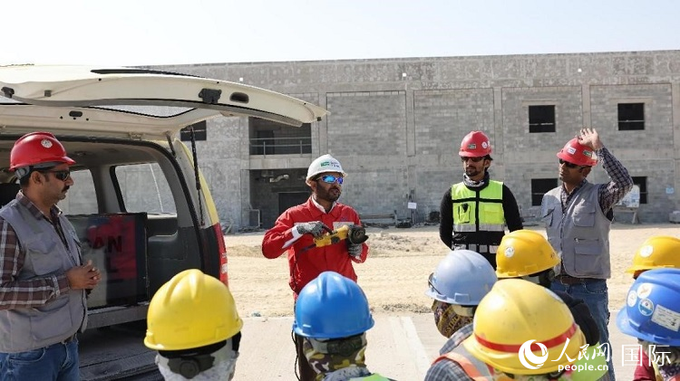 穆薩瓦爾(圖中紅衣人）現(xiàn)場演示工具操作規(guī)范。人民網(wǎng)記者 管克江攝