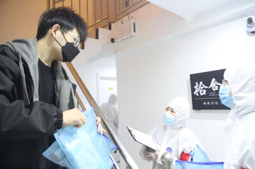 社區(qū)工作人員和志愿者身穿防護服上門送馬應龍大健康防疫包。徐帥攝