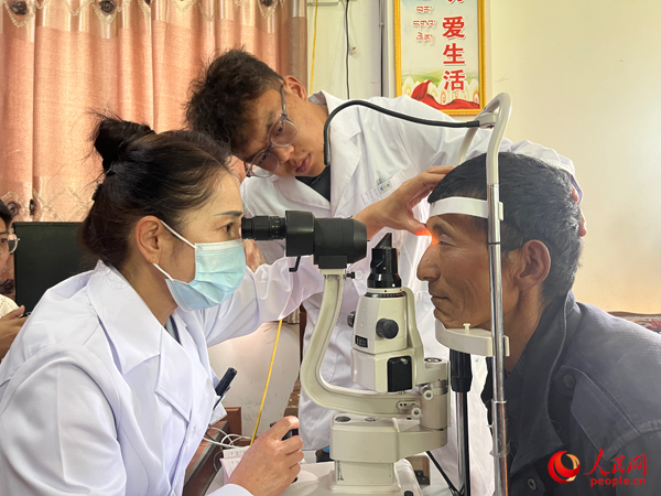 王紅英（左）和團(tuán)隊(duì)成員為達(dá)熱村村民檢查眼睛。人民網(wǎng)記者 杜燕飛攝