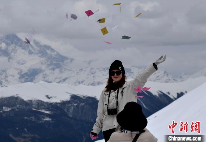圖為5月14日，游客在西藏林芝色季拉山觀景臺(tái)拋灑“隆達(dá)”(風(fēng)馬旗，藏族民眾的一種祈福方式)?！±盍?攝