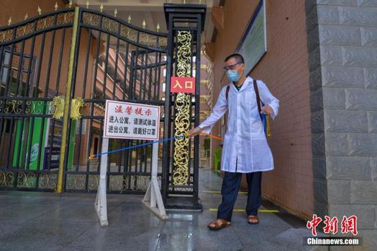 資料圖：海口經(jīng)濟(jì)學(xué)院的工作人員在學(xué)生宿舍樓入口消毒。 中新社記者 駱云飛 攝