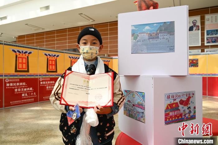 圖為一名獲獎(jiǎng)學(xué)生與自己的繪畫作品合影?！≮w朗 攝