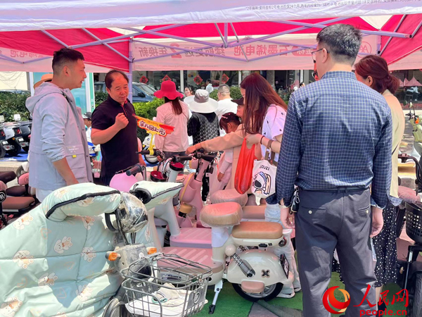 某電動自行車品牌工作人員向消費者介紹以舊換新相關(guān)情況。人民網(wǎng)記者 杜燕飛攝