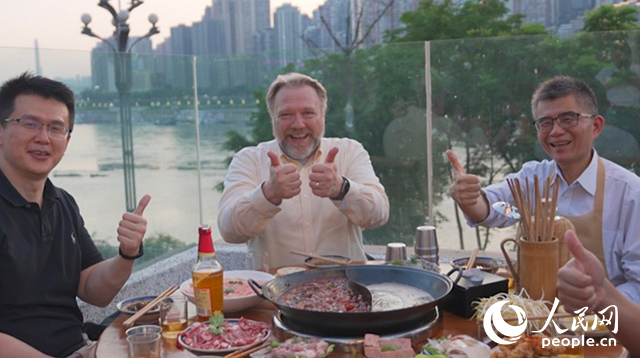 康寧顯示科技事業(yè)部全球拓建項(xiàng)目總監(jiān)軻寶華（中）和同事在重慶南濱路吃火鍋。人民網(wǎng)記者 蘇纓翔攝