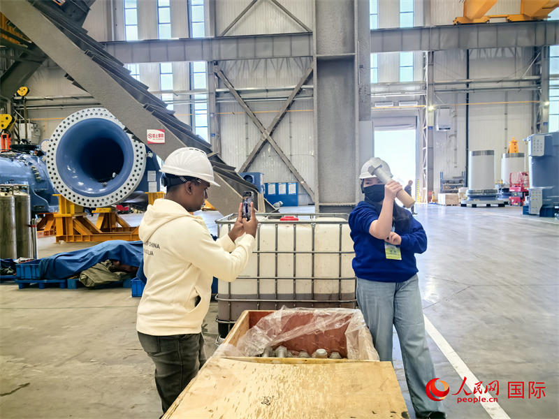 外媒記者掂量廠房內(nèi)的巨型螺栓。人民網(wǎng) 楊春燕攝