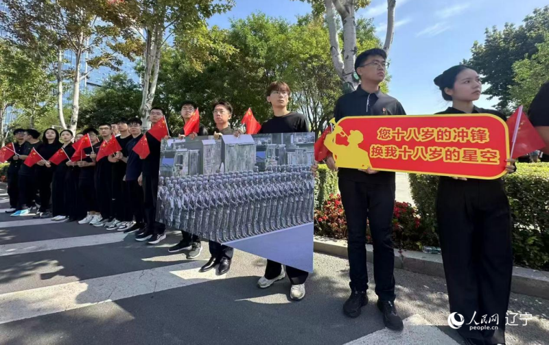 沈陽市人民廣場上，大學(xué)生們手持閱兵的圖片，告慰英烈。人民網(wǎng)記者 周頌雪攝