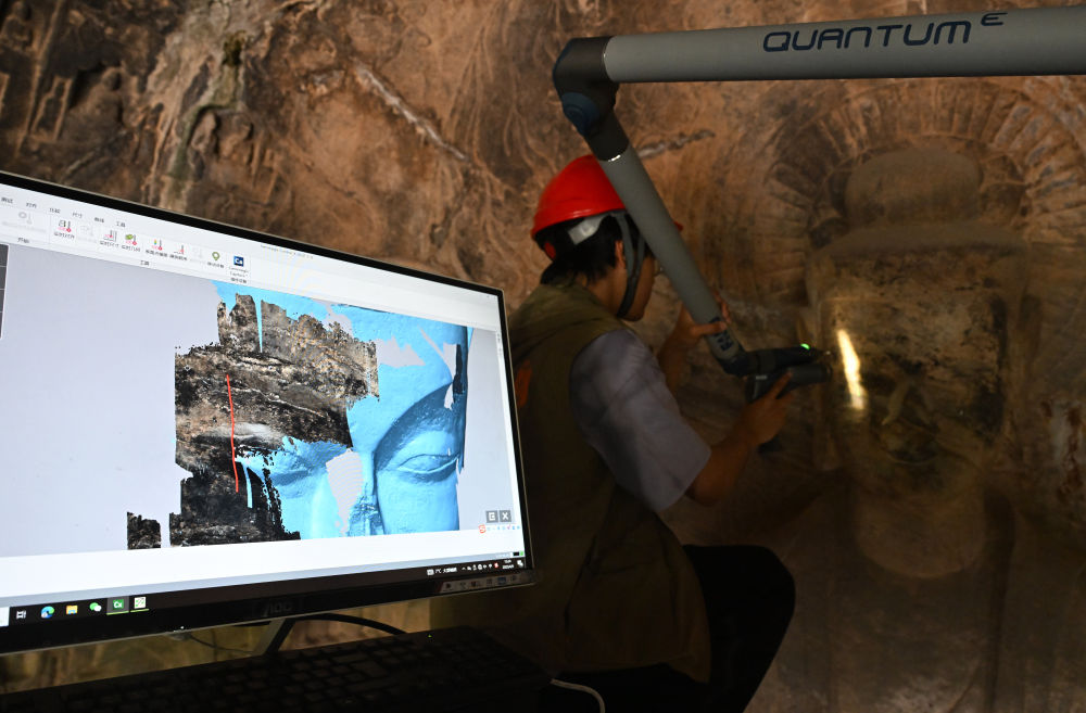 2025年4月9日，武漢大學(xué)文化遺產(chǎn)智能計算實驗室團(tuán)隊成員在魏字洞使用關(guān)節(jié)臂掃描儀對佛像進(jìn)行數(shù)字化掃描。圖片來源新華社