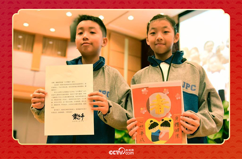 圖為香港“少年警訊”成員郭宏晞（左）展示習(xí)主席回信、羅顥凝（右）展示送給習(xí)主席的賀卡并合影。