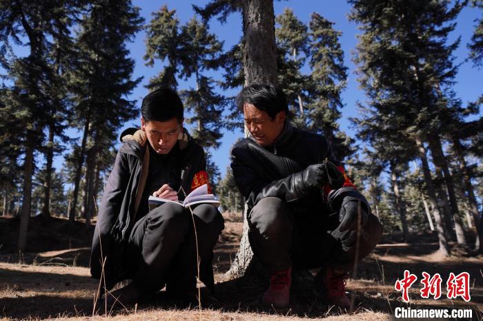 圖為桑杰加(左)和同事記錄巡查結(jié)果。　馬銘言 攝