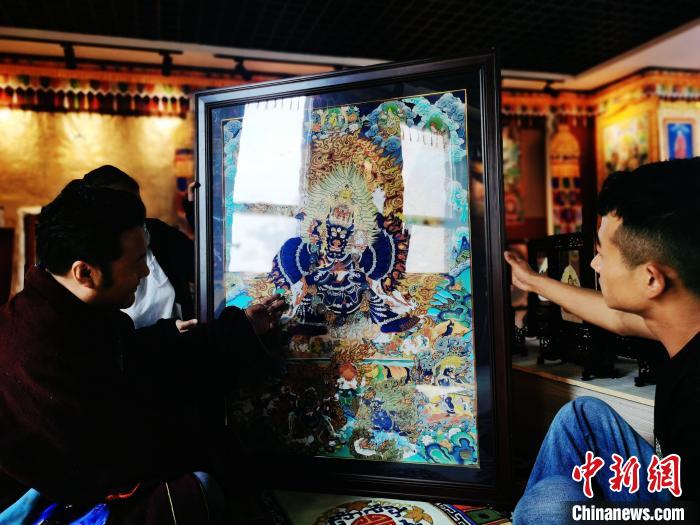 圖為久美尖措(左)與徒弟們展示唐卡作品?！?zhí)砀?攝