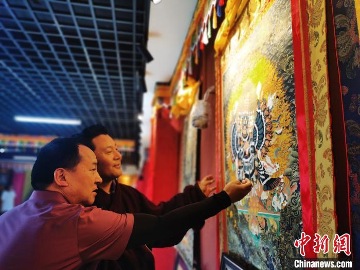 圖為久美尖措展示唐卡作品?！?zhí)砀?攝