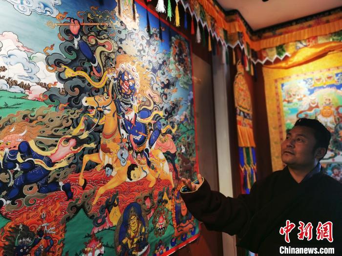 圖為久美尖措展示唐卡作品?！?zhí)砀?攝