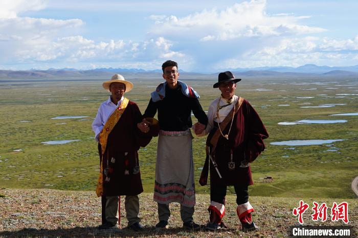 圖為一名留學生身穿自己國家的服飾和藏族民眾合影留念。　馬銘言 攝