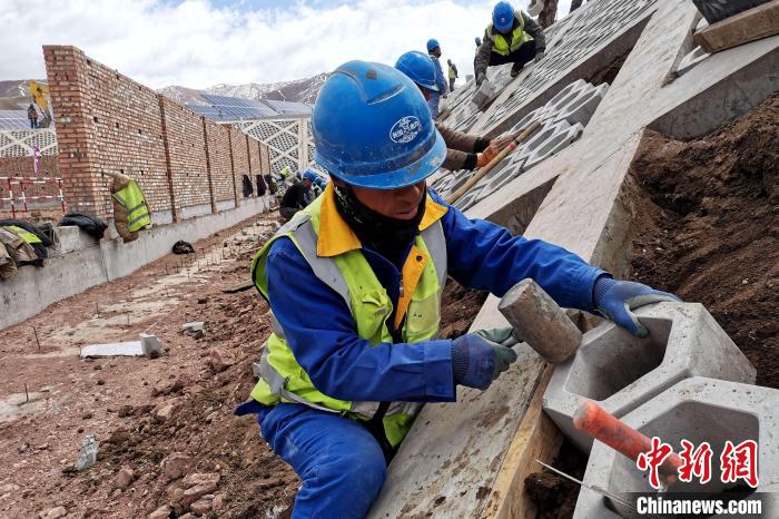圖為光伏發(fā)電項目施工區(qū)工人在護坡鋪設空心磚?！±铍h 攝