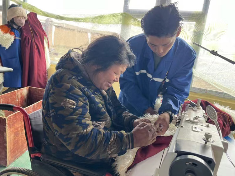 扎西奪爾登幫助殘疾員工裁剪。阿壩州文明辦供圖