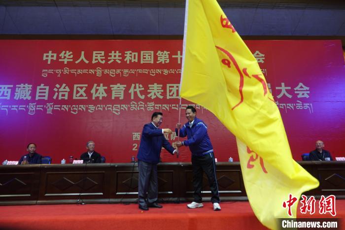 西藏自治區(qū)副主席甲熱·洛桑丹增授代表團團旗，西藏自治區(qū)體育局局長尼瑪次仁接旗?！∪轿木?攝