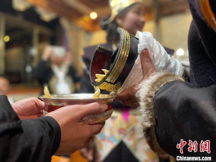 圖為主人在碗中斟滿青稞酒?！∪轿木?攝