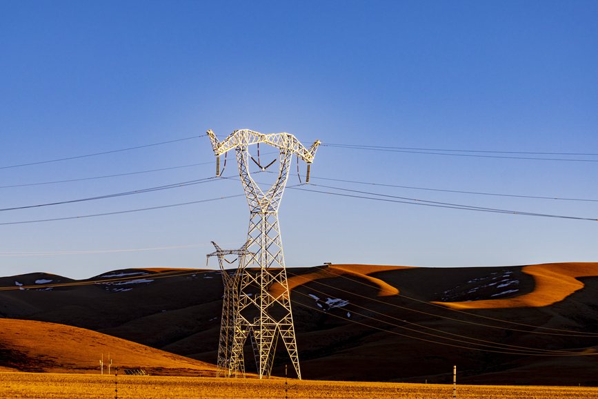 阿里地區(qū)的曠野上，電力鐵塔在夕陽下熠熠生輝。