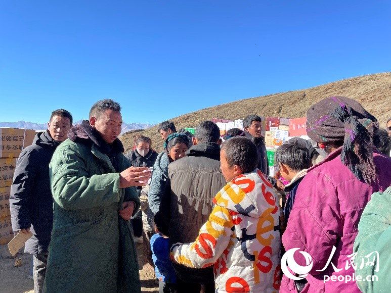 定日縣公安局干警頓珠次仁（左二）正在協(xié)助分發(fā)物資。人民網(wǎng)記者 郝潔攝