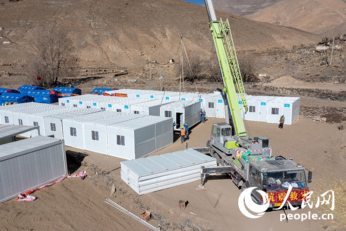 1月9日，在日喀則市定日縣長所鄉(xiāng)古榮村安置點(diǎn)，救援人員和施工人員合力抓緊搭建移動(dòng)板房，確保受災(zāi)群眾溫暖過冬。人民網(wǎng)記者 翁奇羽攝