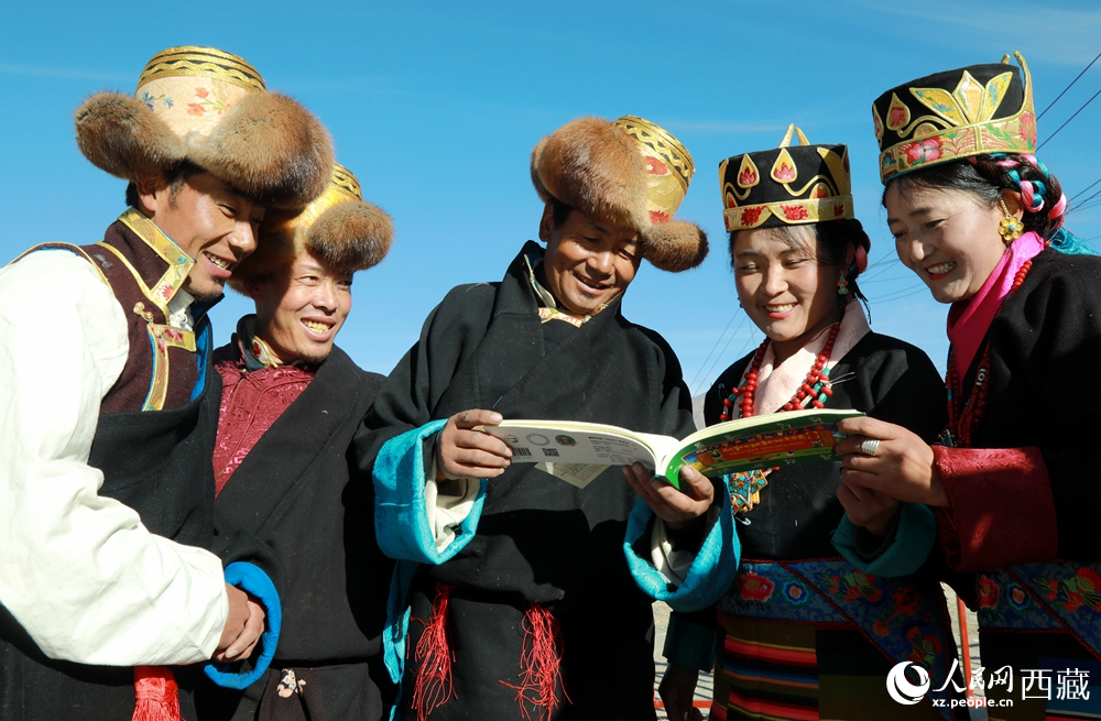 鄉(xiāng)親們身著民族盛裝，圍站在一起認(rèn)真翻看日歷，共話農(nóng)事安排與時節(jié)規(guī)律，笑容洋溢傳遞豐收期盼。人民網(wǎng)記者 吳雨仁攝